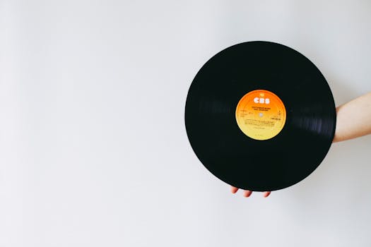 A person's hand holding a classic vinyl record against a solid white background.