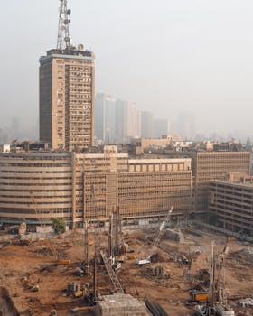Aerial view of Cairo construction site with hazy skyline and high-rise buildings in Egypt.
