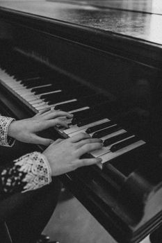 Close-up black and white photo of hands playing a piano, conveying elegance and musical artistry.