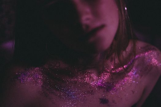 A captivating image of a woman with shimmering pink and purple glitter on her skin, creating an artistic glow.