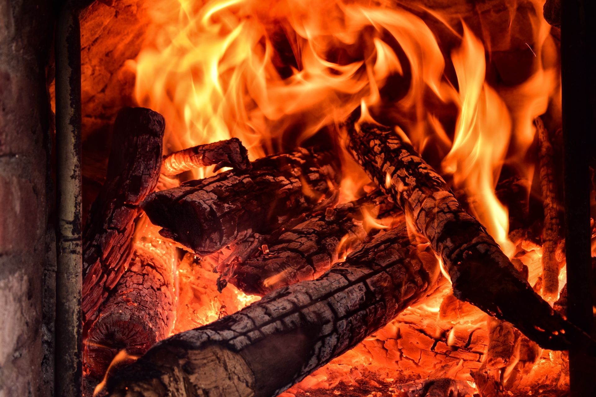 Close-up of vibrant flames and burning wood in an indoor fireplace, creating a warm ambiance.
