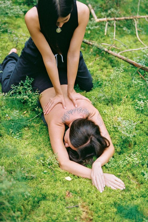 Free A serene outdoor massage scene with a woman lying on green grass for relaxation. Stock Photo