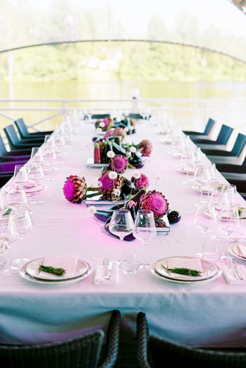 Free An elegant outdoor banquet table set with purple floral decorations and glassware. Stock Photo