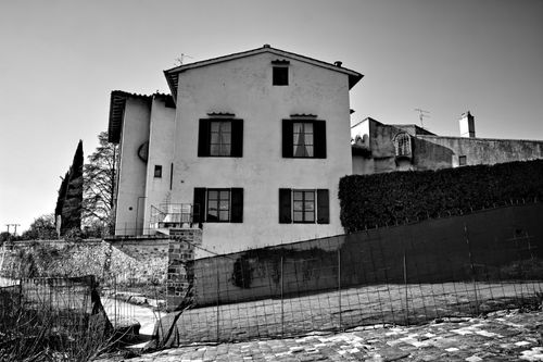 Free Black and white photo of a European-style house with cobblestone street and trees. Stock Photo