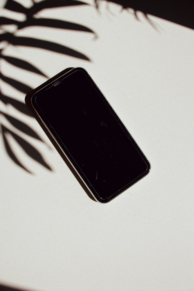 Iphone In Shadow Of Leaf On Table