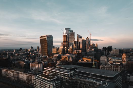 Breathtaking aerial view of London's modern skyline with iconic skyscrapers illuminated by the sunset.