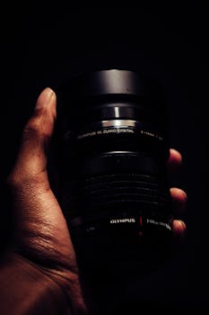 黑暗背景下，握住相机镜头的手的详细视图