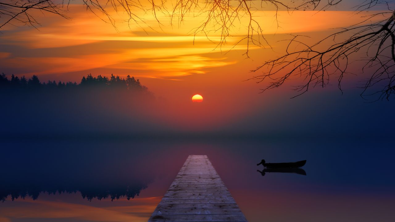 calm evening sunset over a foggy lake with a wooden dock and silhouett