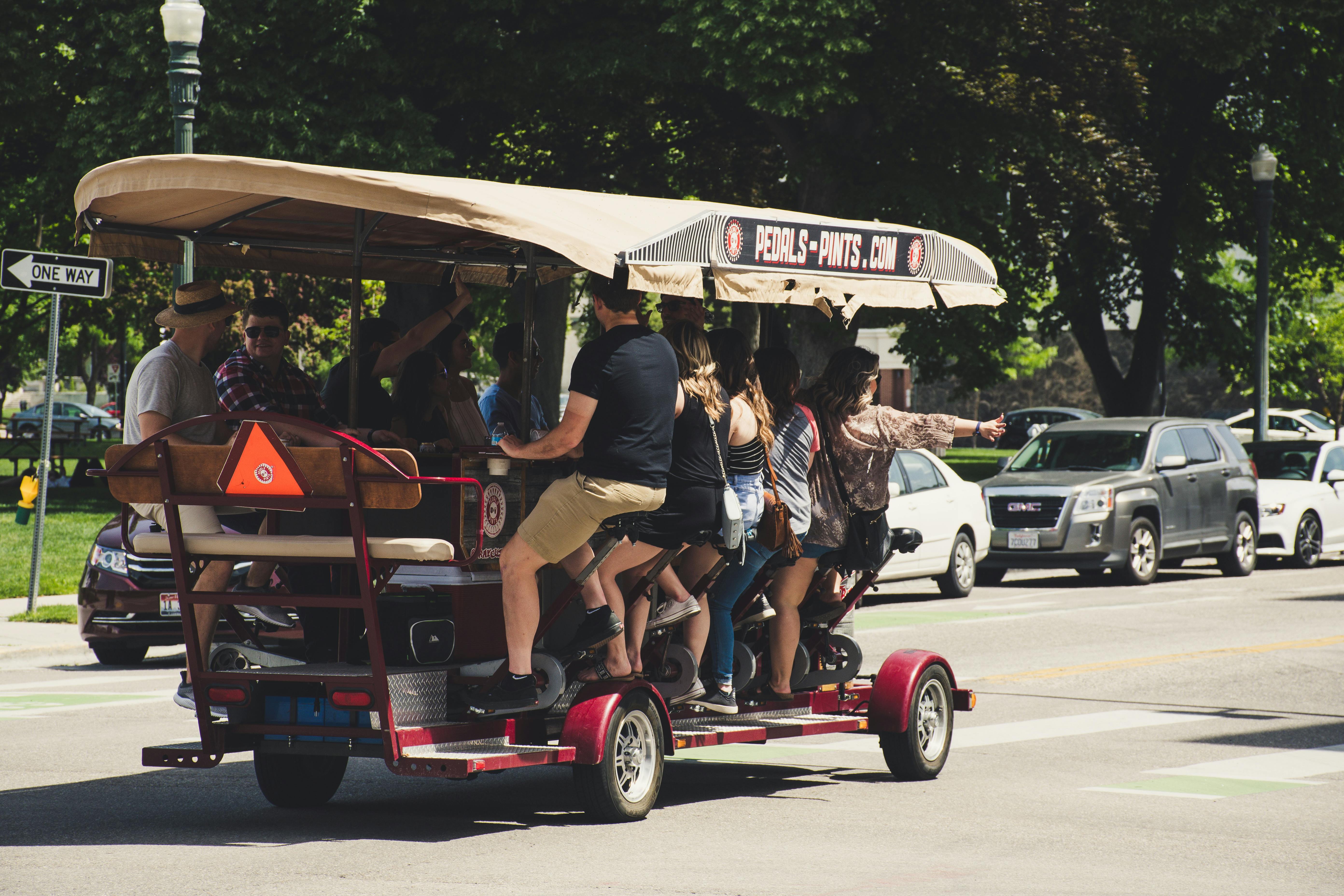 A group of people riding a pedal-powered cart on a sunny day, enjoying a unique social outing.