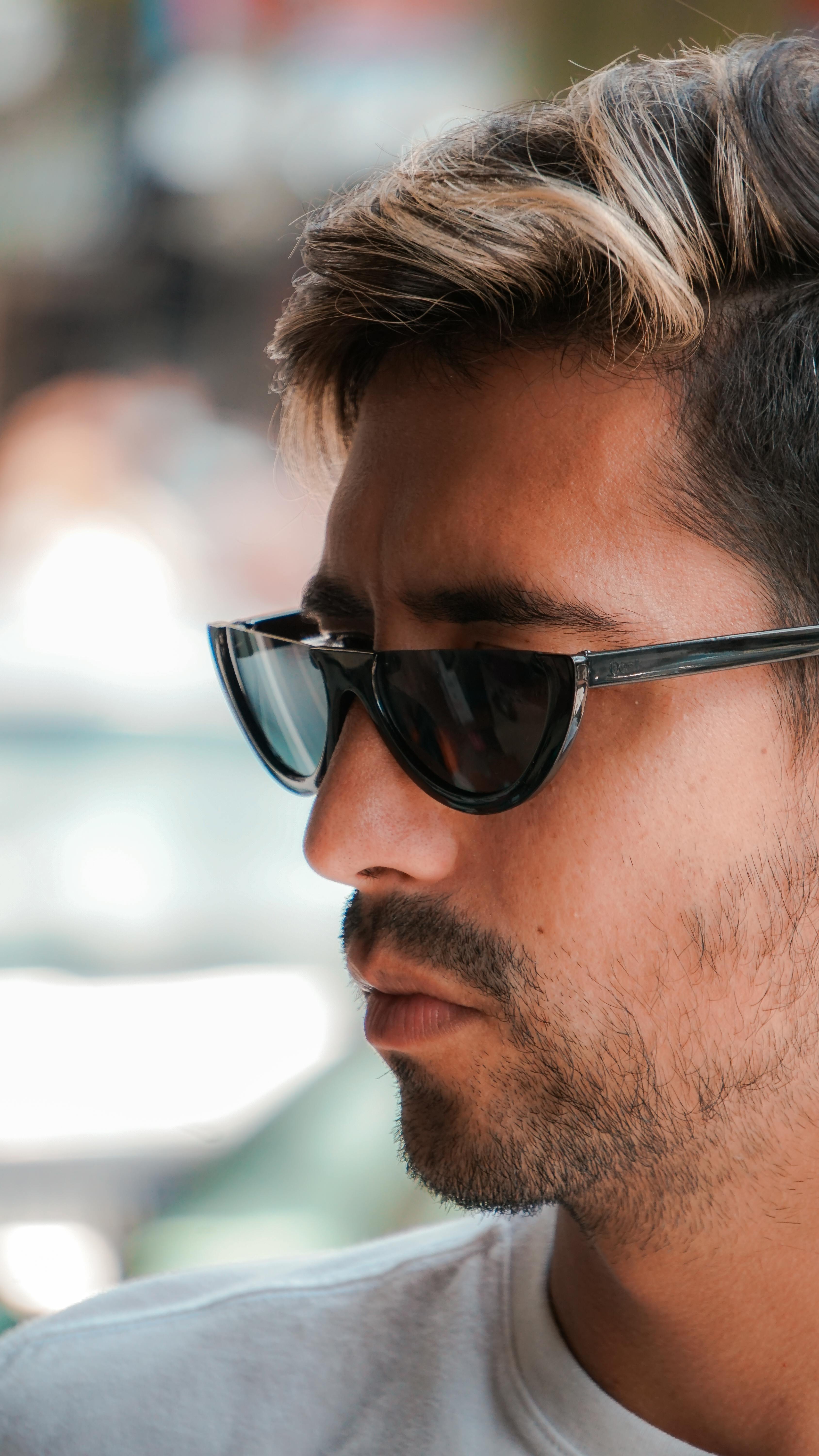 Close-up profile of a bearded man wearing sunglasses in an outdoor setting.