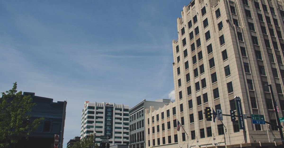 A bustling city street view with modern architecture and high-rise buildings under a clear sky.