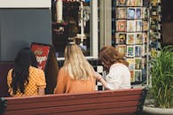 三名女子坐在古董店外的长凳上，享受着外出的一天