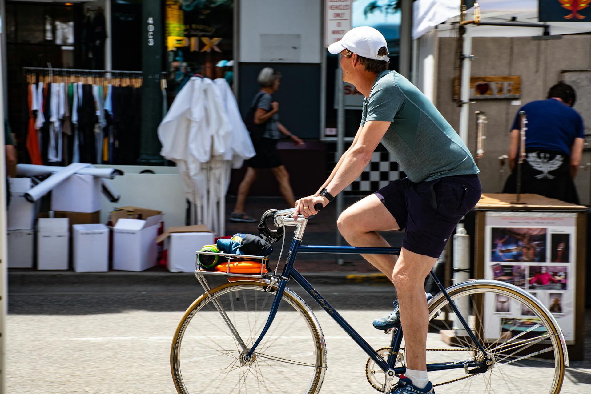 A cyclist rides a bicycle through a bustling urban market area, showcasing an active lifestyle.