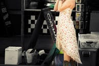 一名穿着花卉连衣裙的女子，被坦率地拍摄于繁忙的街角，那里有购物标志