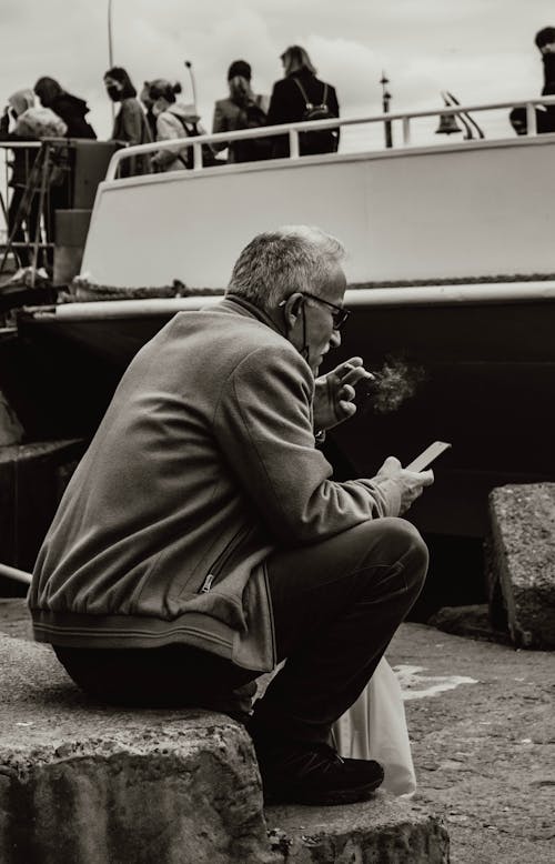 An Elderly Man Smoking while using his Smartphone