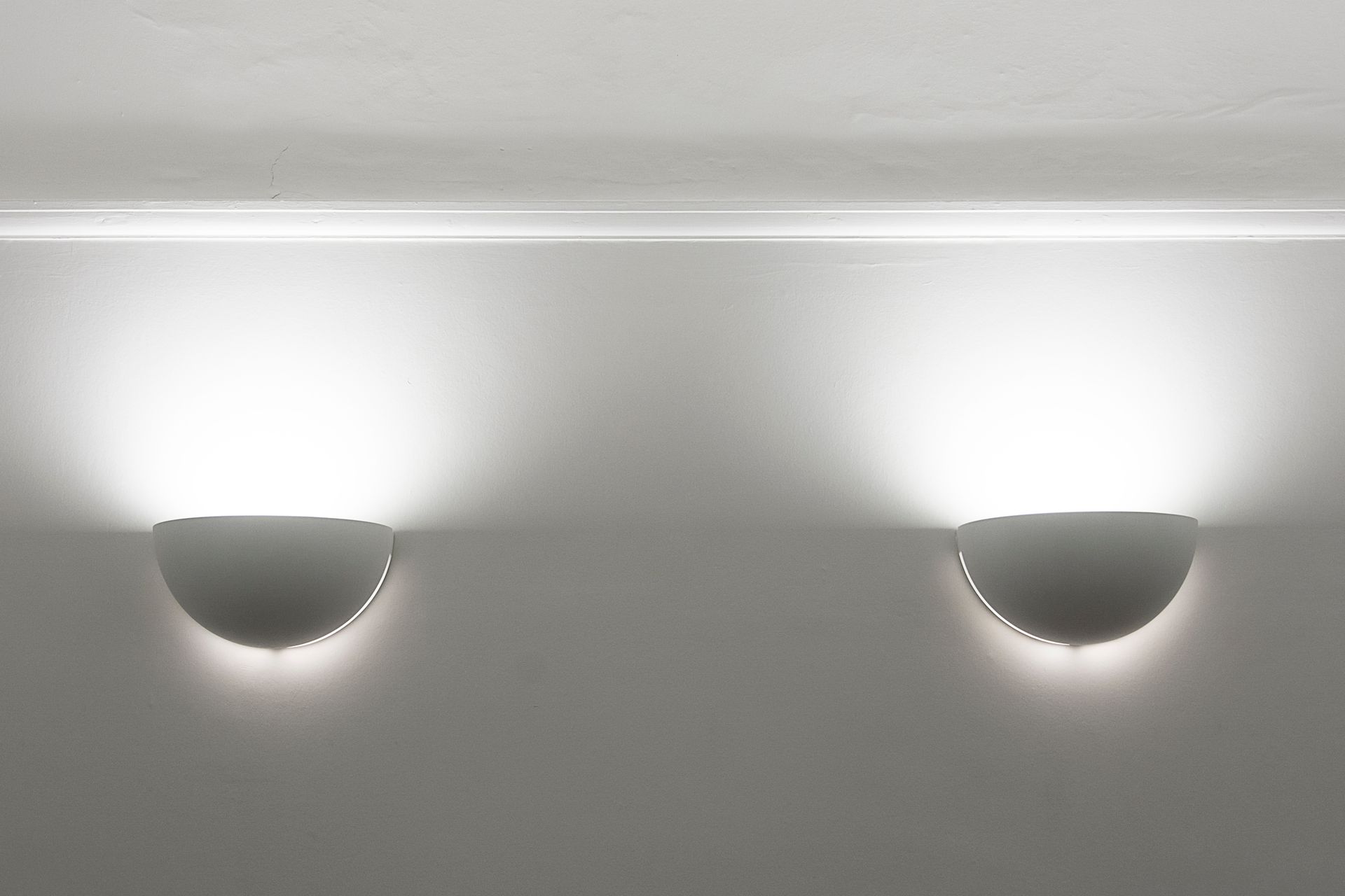 Elegant modern wall sconces casting ambient light on a plain white ceiling.