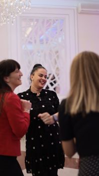 Women in stylish attire sharing a joyful moment in a beautifully decorated indoor space.