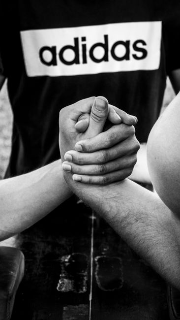Black and white close-up of two hands engaged in an intense arm wrestling match.