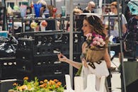 一名妇女在户外市场快乐地购物，手里拿着玫瑰