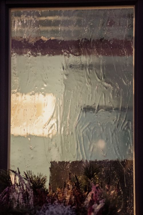 Free Close-up of raindrops on a window creating an abstract and creative pattern with blurred outdoor landscape. Stock Photo