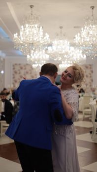A joyful couple dancing under luxurious chandeliers at a formal indoor event, capturing romance and elegance.