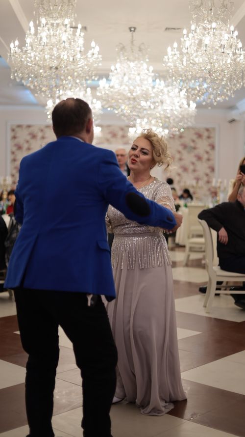 Free A couple elegantly dancing at a glamorous reception with chandeliers overhead. Stock Photo