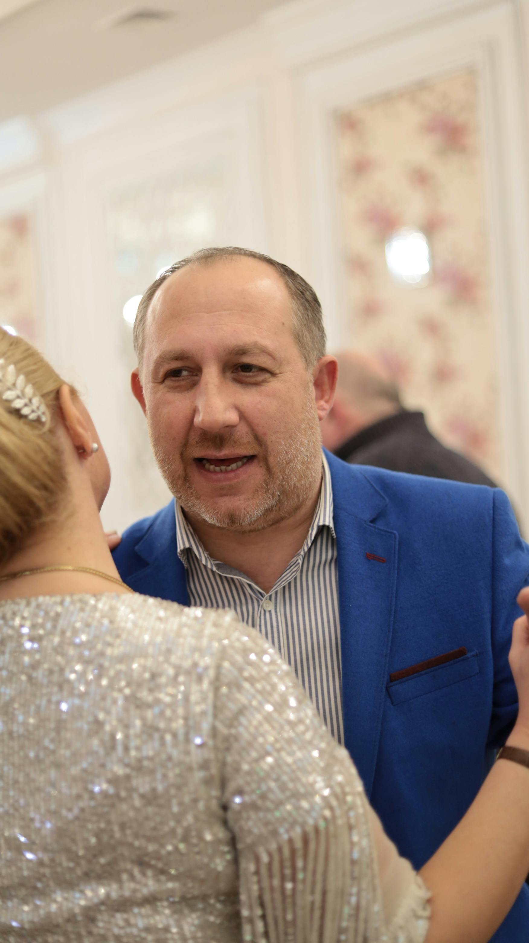 a man in blue coat talking to the person in front of him