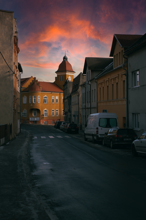 Free A quaint European street scene with colorful skies and classic architecture at sunset. Stock Photo