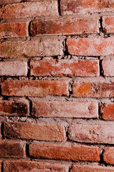 Detailed view of a rustic red brick wall showcasing its rough texture and color variations.