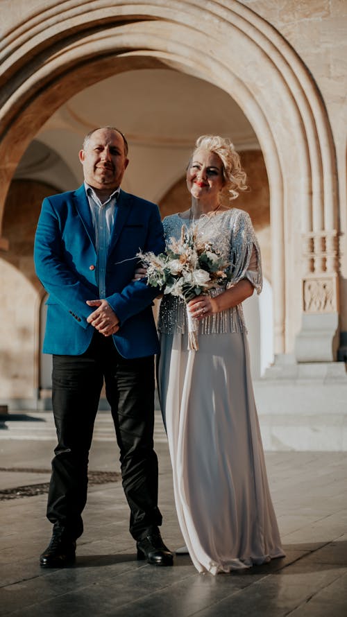 A Man in Blue Suit Jacket Standing Beside the Woman in Gray Dress