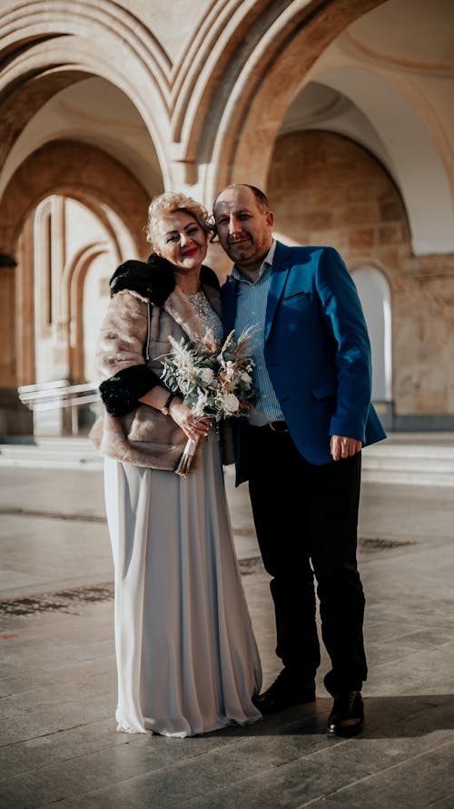 A Man in Blue Suit Standing Beside Woman in Dress