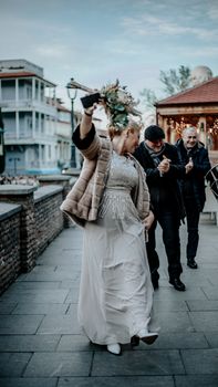 Bride dancing outside with friends celebrating at a wedding ceremony.