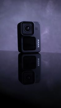 Close-up of a GoPro camera on a black reflective surface, showcasing its design.