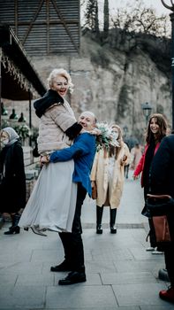 Elderly couple celebrating joyfully outdoors among friends.