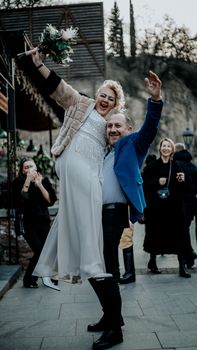 Bride and groom joyfully celebrating their special day with friends outdoors.