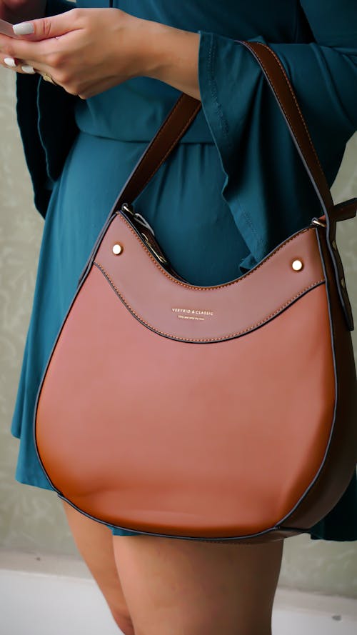 A Person in Blue Dress Carrying Brown Elegant Handbag