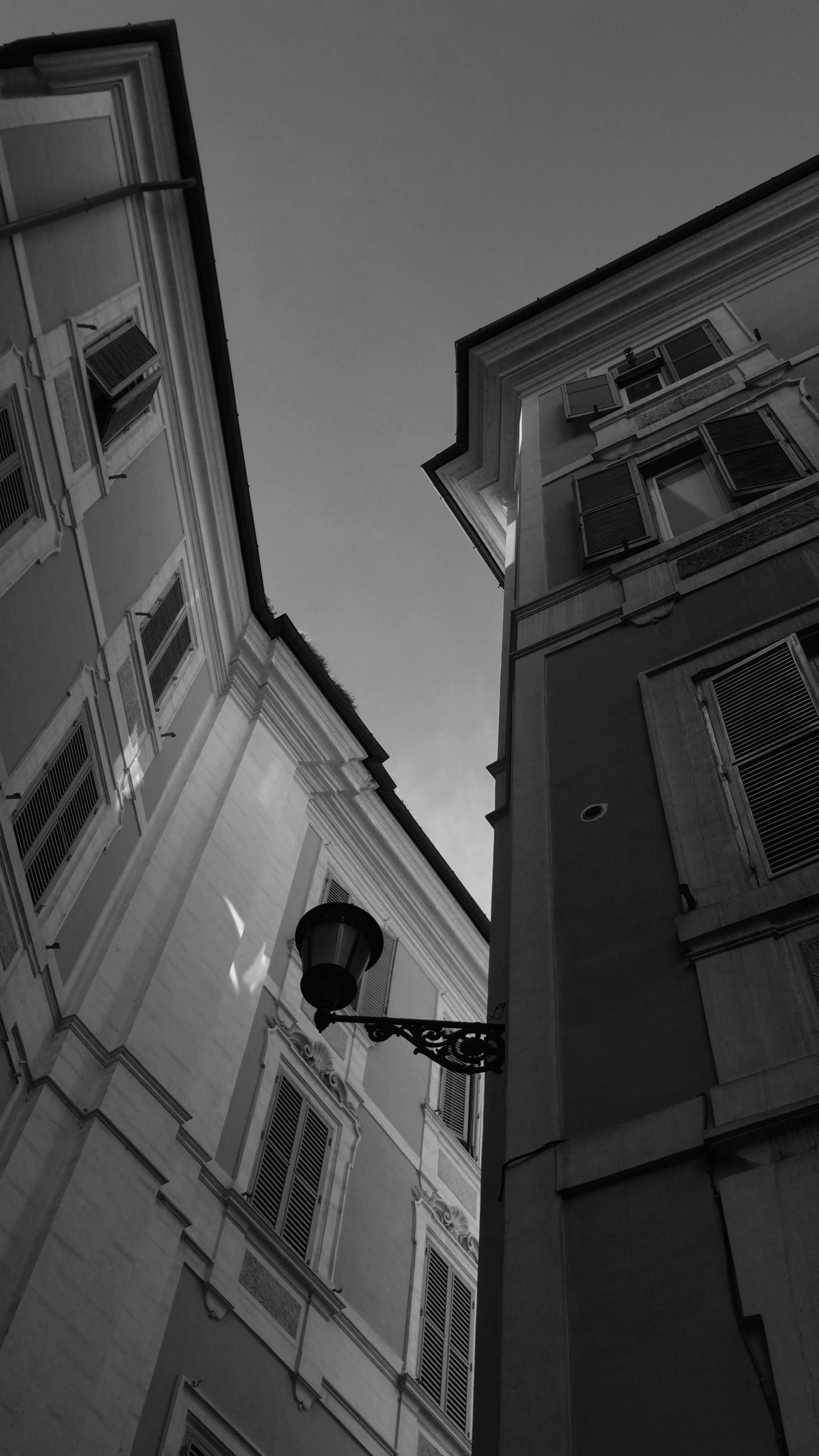 Low-angle black and white photo capturing historic Italian buildings against a clear sky.