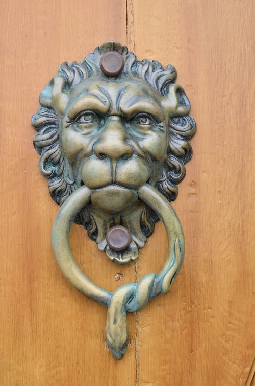 Free Antique brass lion head door knocker on a rustic wooden door, blending vintage and classic styles. Stock Photo
