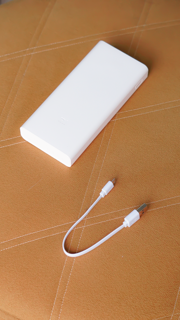 White power bank and charging cable on a textured brown surface, perfect for technology themes.