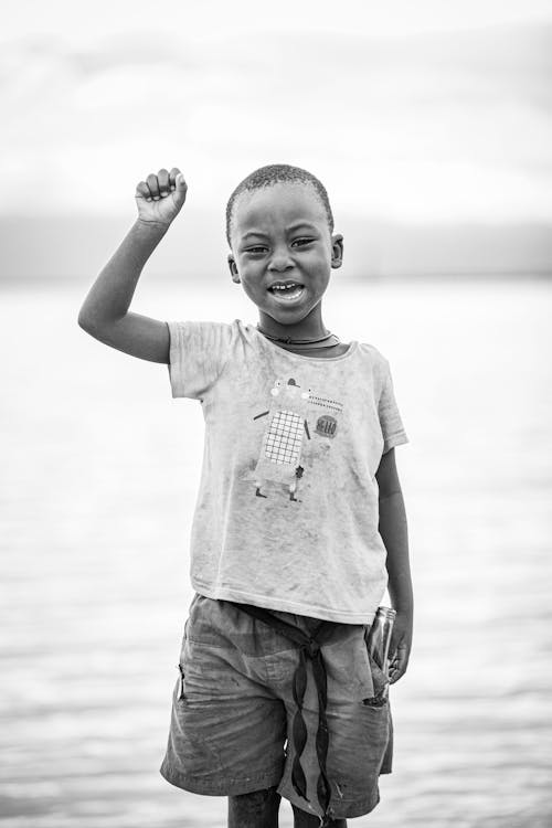 A Grayscale Photo of a Young Boy Raising His Hand
