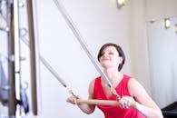 在明亮的室内健身房里，健美的女性正用阻力设备锻炼