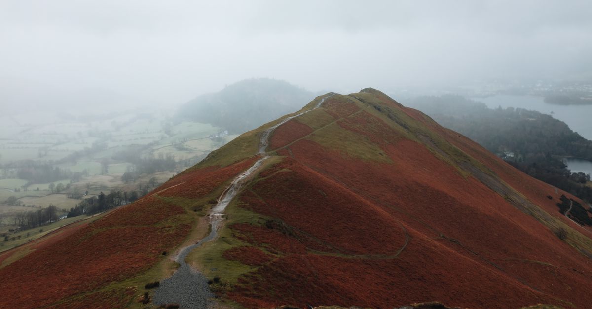 Explore the misty paths of Cat Bells overlooking the serene landscapes of Cumbria, England.