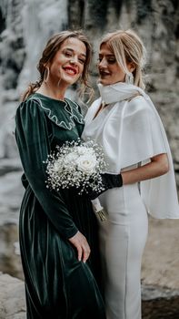 Elegant bridal portrait with bride and bridesmaid smiling outdoors in vintage attire.