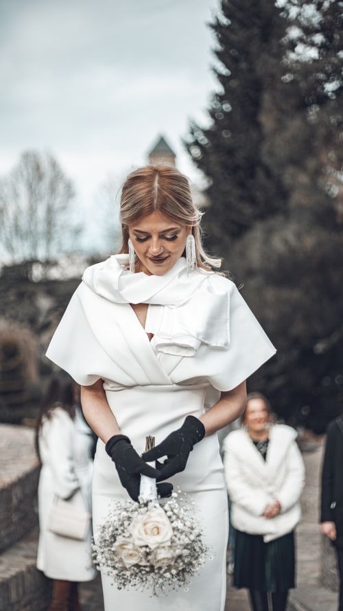 Free Elegant bride in white dress holding bouquet, outdoor wedding setting. Stock Photo