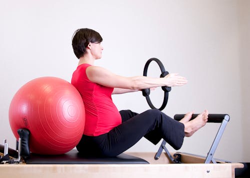 Wanita Berkemeja Merah Duduk Di Perlengkapan Fitness