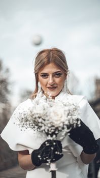 A bride in a white dress holds a beautiful bouquet, exuding elegance and joy in an outdoor setting.