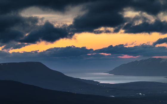 A breathtaking view of mountains and river under a dramatic twilight sky.