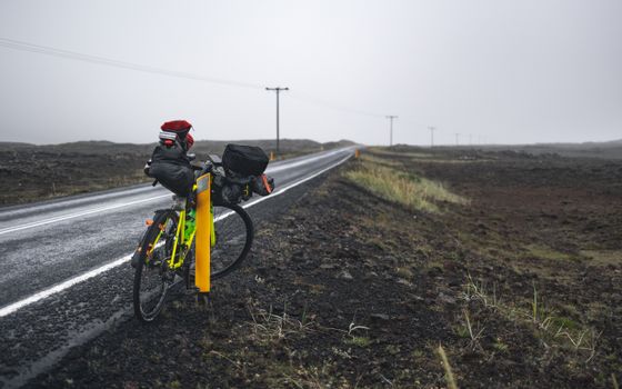 A bicycle loaded with bags parked on a roadside, hinting at long-distance travel and adventure.