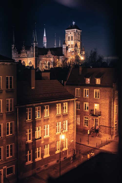 Free A beautiful view of a cityscape featuring an illuminated cathedral and surrounding buildings at night. Stock Photo