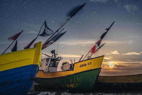 Foto d'estoc gratuïta de banderes, barques de pesca, capvespre